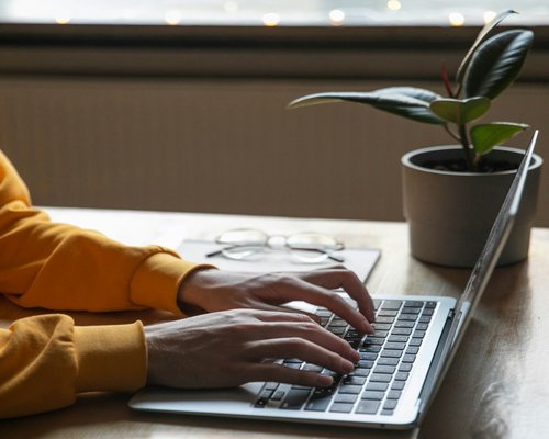 Person typing on a laptop with a comfortable posture at home