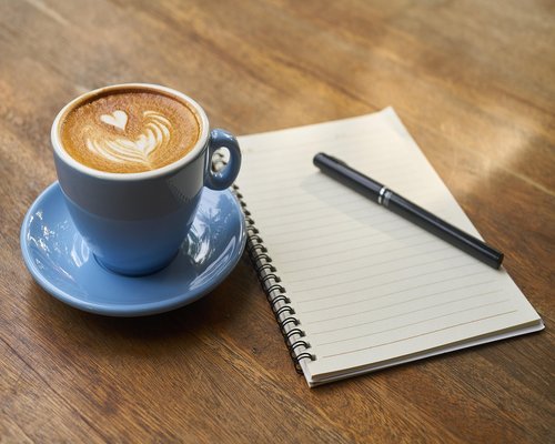 Coffee cup and notebook on an office desk