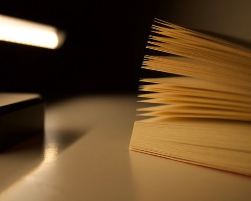 Reading lamp casting warm light on open pages